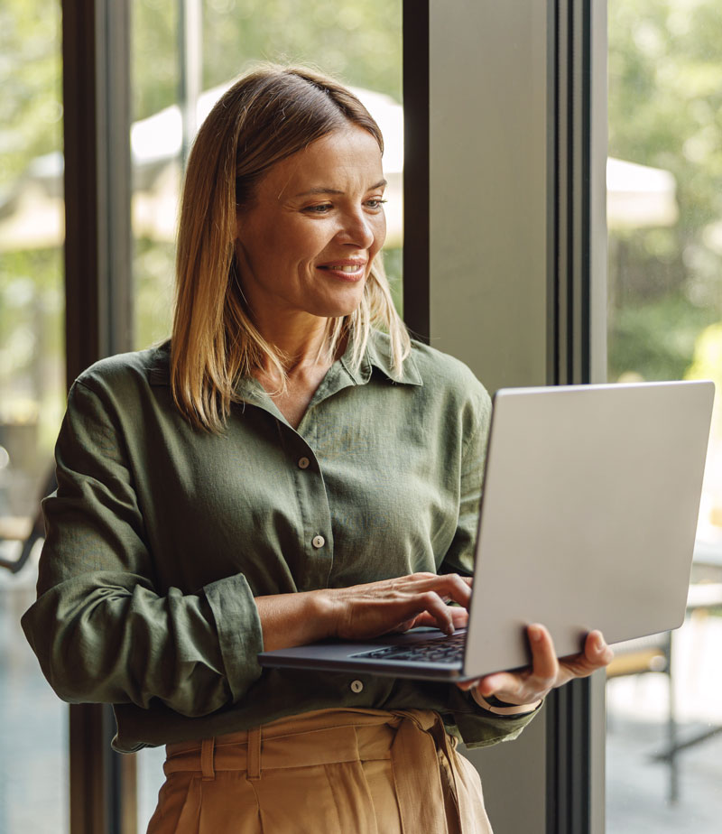 Woman sales manager standing in modern coworking and working on laptop